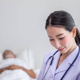 Image portrait-of-smiling-asian-nurse-with-patient-in-background  from Freepik