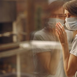 Image of woman-in-mask-stands-by-the-window from Freepik